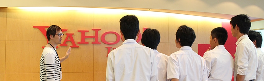 社会貢献活動。壁面のYahoo! JAPANロゴを前に、会社見学の参加者に説明をするヤフー社員の写真。