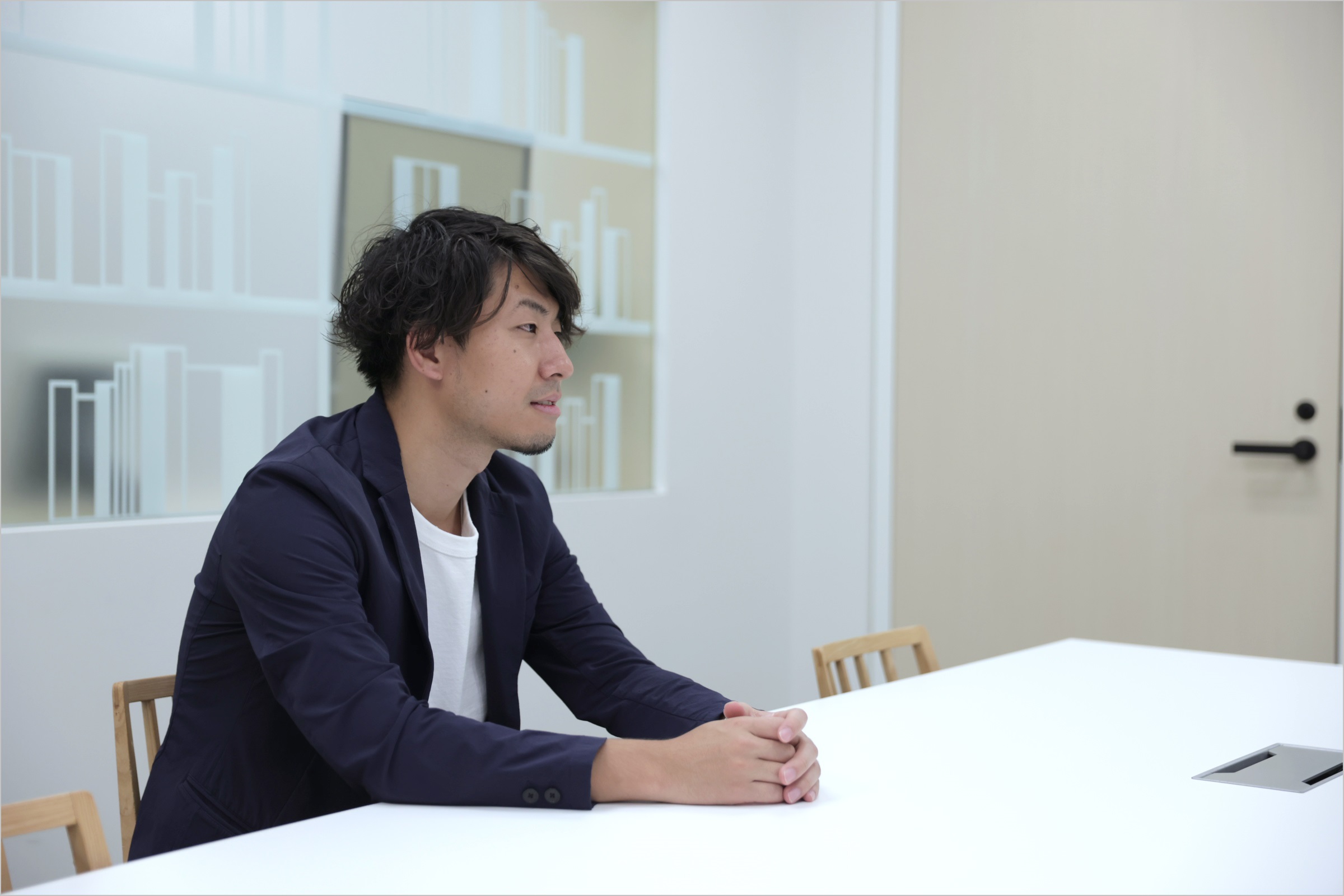 菅原が椅子に座りながら、会社の制度についてインタビューに答えている様子の写真