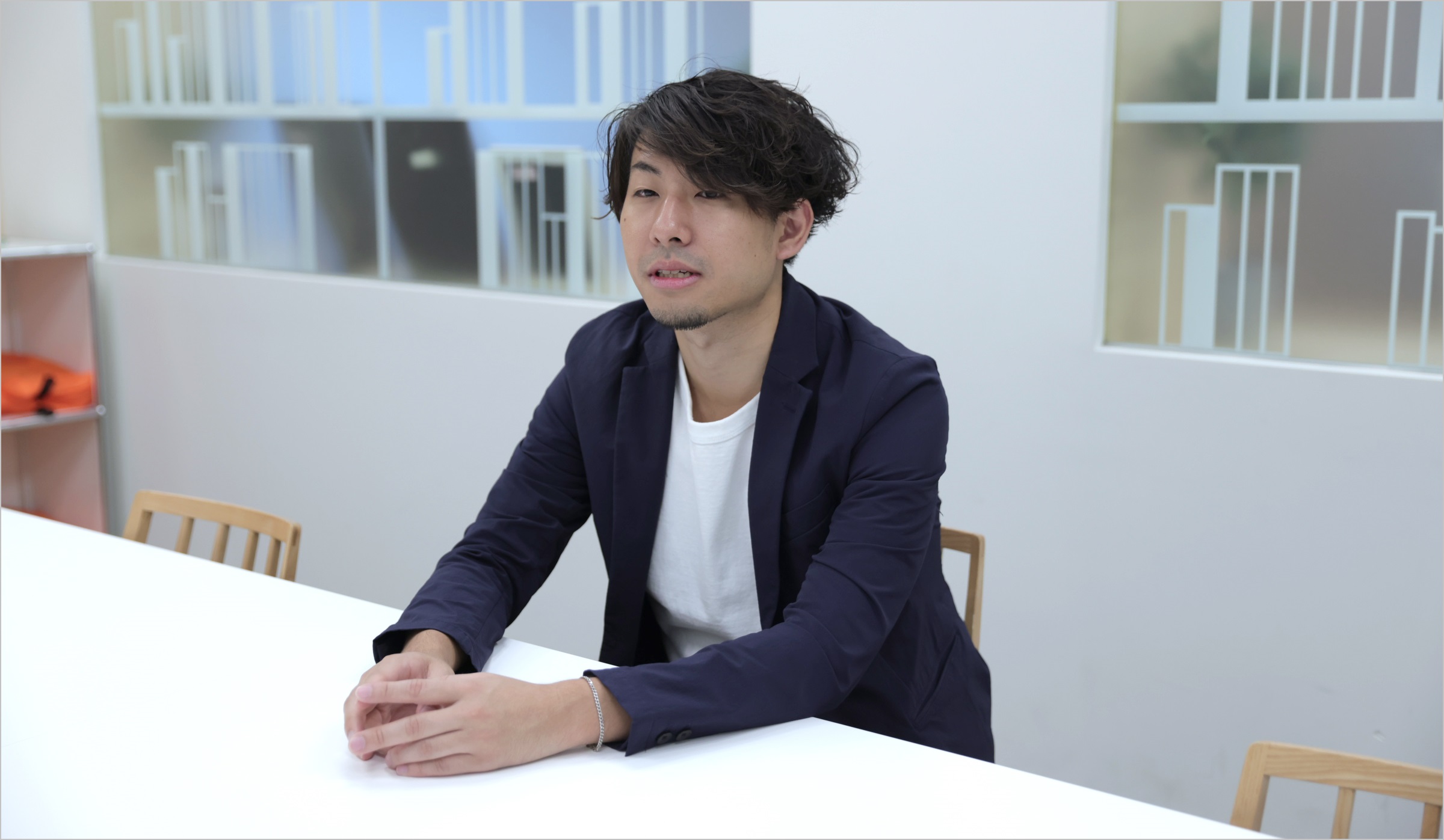 菅原が椅子に座りながら、仕事のやりがいなどについてインタビューに答えている様子の写真