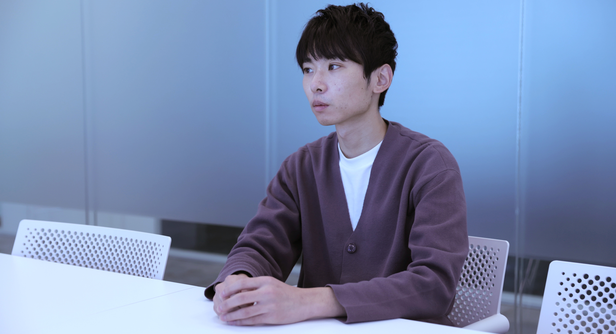 福岡が椅子に座ってに真剣な表情でインタビューに答えている様子の写真