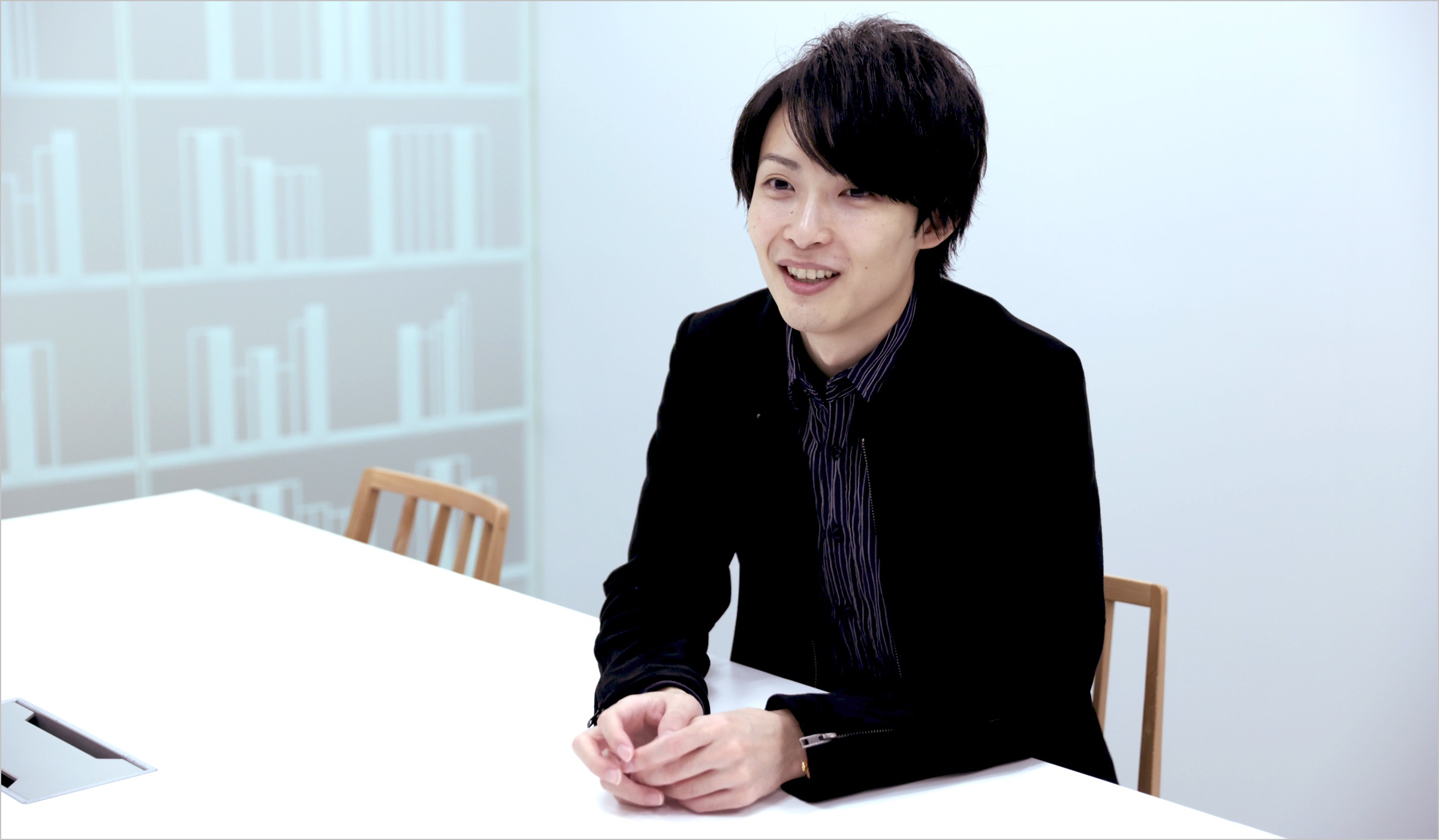 坂本が椅子に座り楽しそうにインタビューに答えている様子の写真