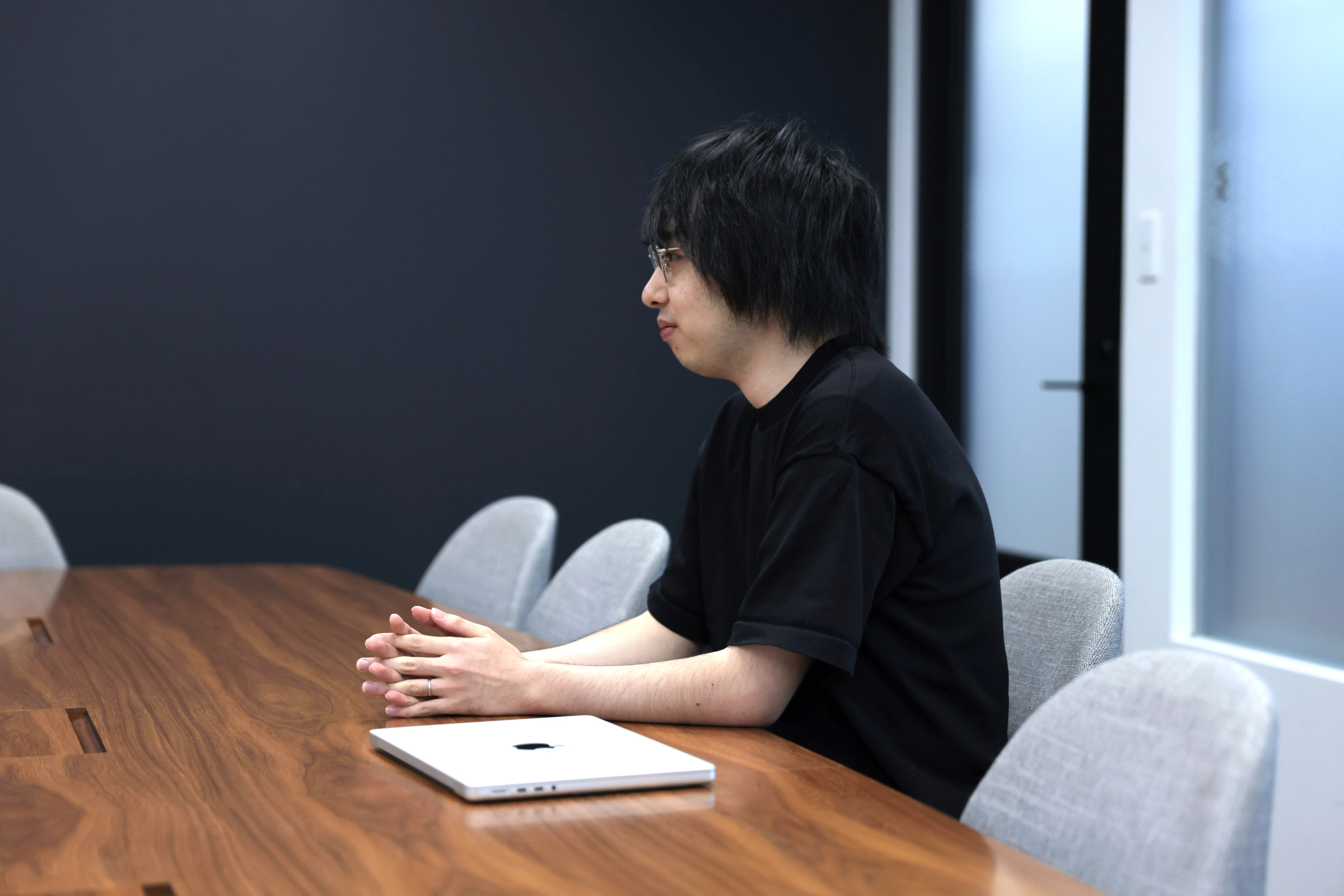 鈴木が椅子に座り、自らの仕事について前向きに語る様子の写真