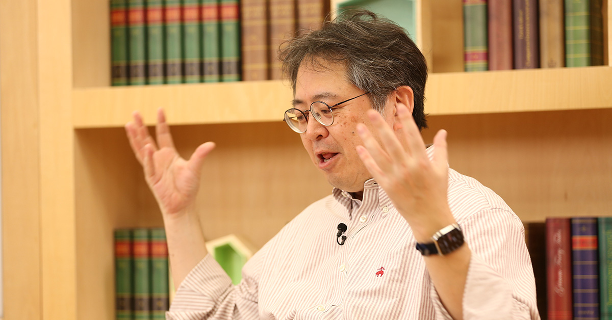 眼鏡をかけた男性が熱心に話している様子。