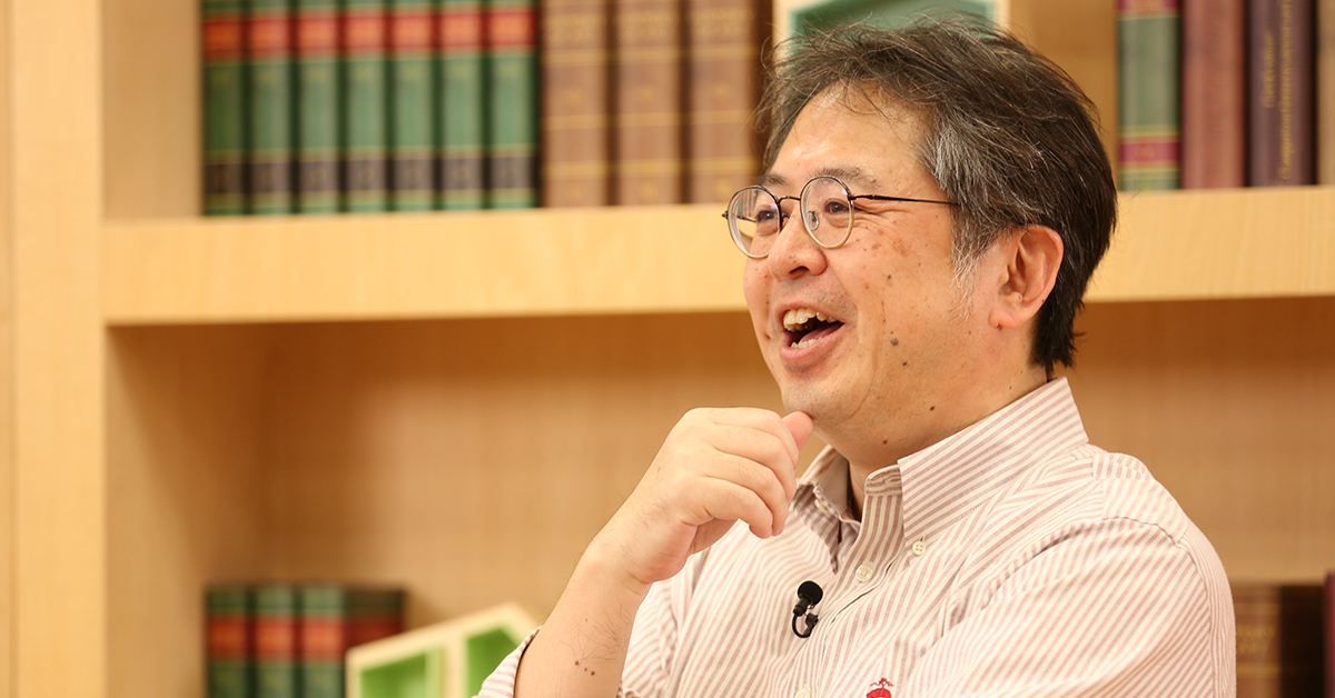 眼鏡をかけた男性が笑顔で話している様子。