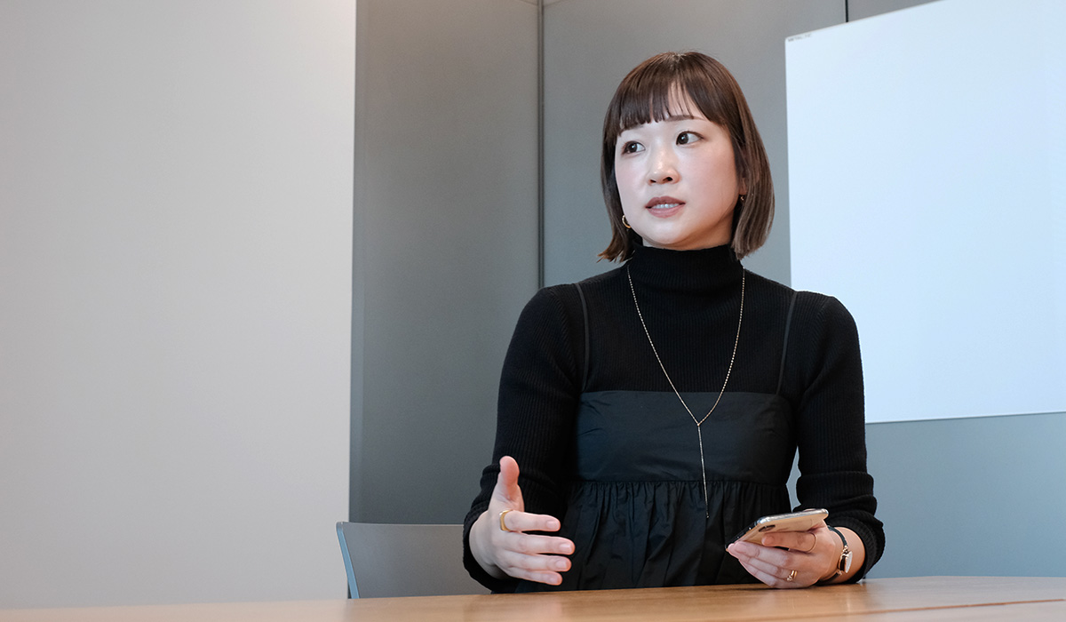黒の服を着た女性が会議室で話している様子。