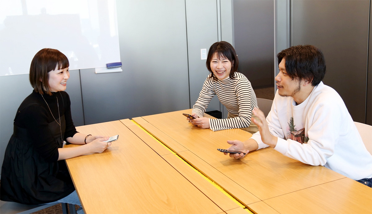 3人がテーブルを囲んで楽しそうに会話している。