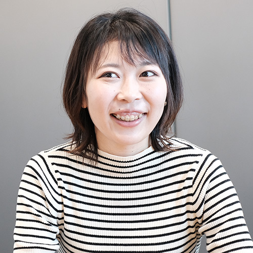 ボーダーのトップスを着た女性が笑顔で話している。