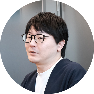 メガネをかけた男性が、リラックスした表情で座っている。