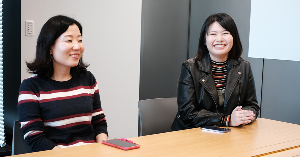 二人の女性がテーブルで笑顔を見せている。