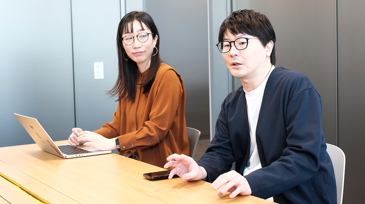 メガネをかけた男女が会議で話している。