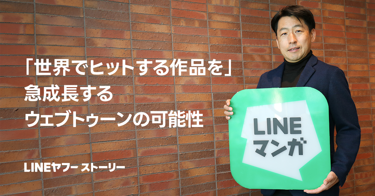 男性が「LINEマンガ」のサインを持ち、壁の前で立っている。