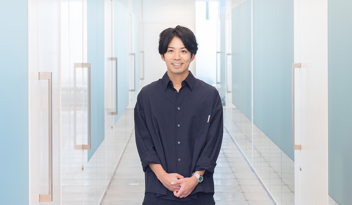 A man stands in a hallway with blue walls, exuding a clean and modern atmosphere.