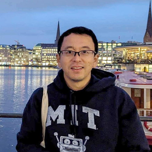 夜景を背景に笑顔の男性が写っている写真。