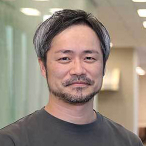 男性がインタビュー中の様子。背景には窓があり、手を広げて話している。
