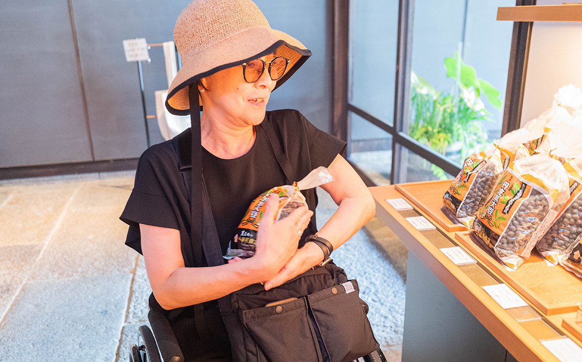 女性が店内で商品を抱えている。帽子とサングラスを着用。