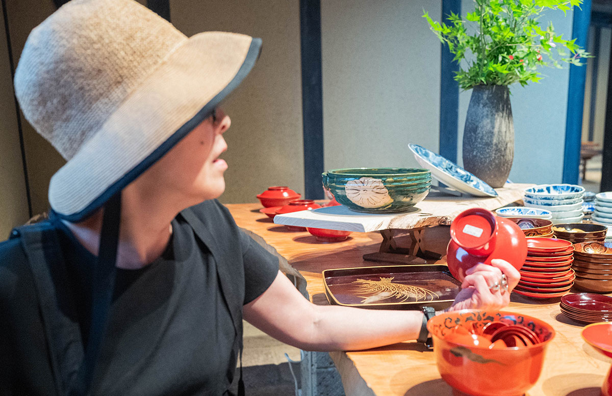 帽子をかぶった女性が陶器の器を手に取っている。