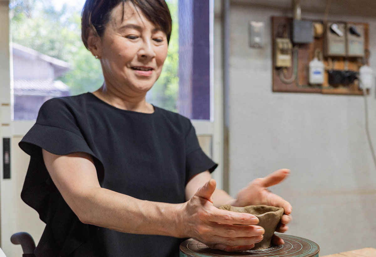女性が陶芸をしている。粘土を手で成形中。