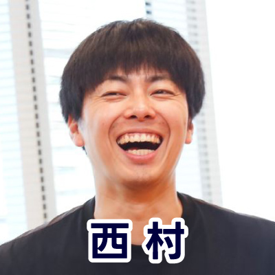 黒いシャツを着た男性がカメラに向かって笑顔を見せている。明るい室内で撮影。西村さんのアイコン。