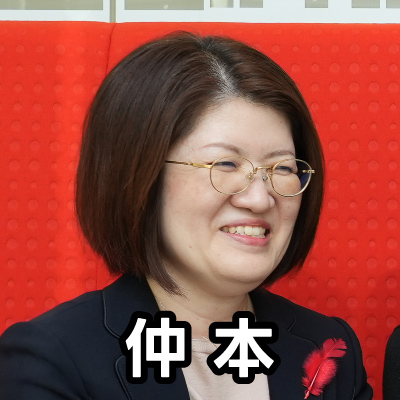 眼鏡をかけた女性が笑顔で座っており、「仲本」と書かれたテキストが重ねられています。