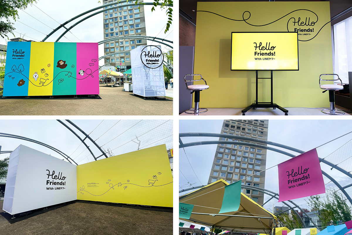 「Hello Friends!」と書かれたカラフルなパネルが展示されています。屋外イベントの様子を示しています。
