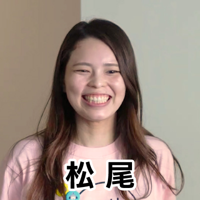 女性が笑顔でカメラを見つめています。背景はシンプルで、彼女の明るい表情が際立っています。