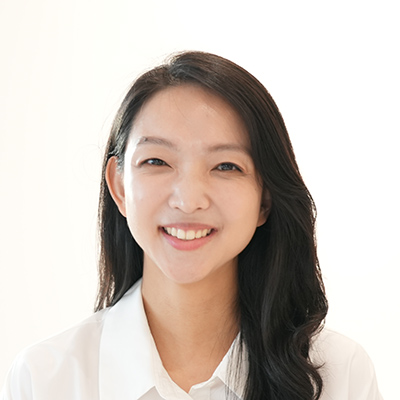 女性が微笑んでいるポートレート写真です。白い背景がシンプルで、明るく清潔な印象を与えます。
