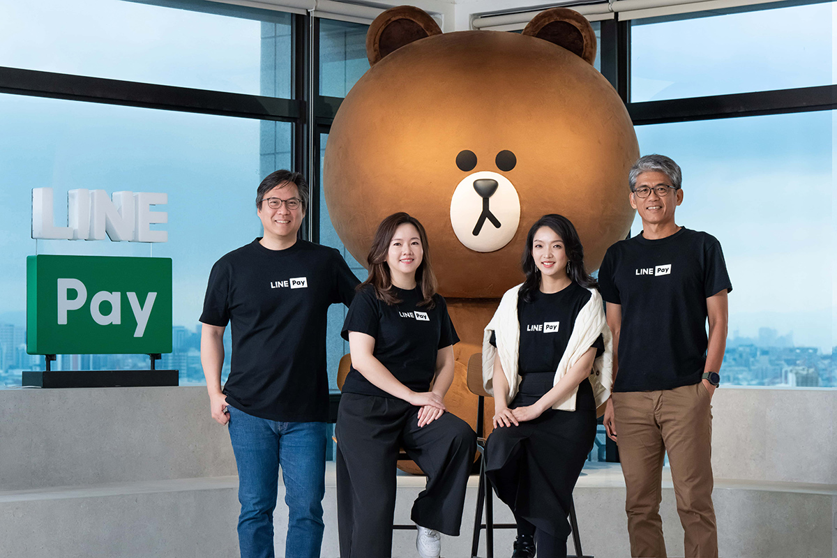 LINE PayのTシャツを着た4人が、巨大なクマのぬいぐるみの前でポーズ。