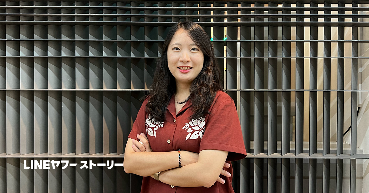 女性が腕を組んで立っている。背景にはデザイン性のある壁があり、LINEヤフーストーリーの一環として紹介。