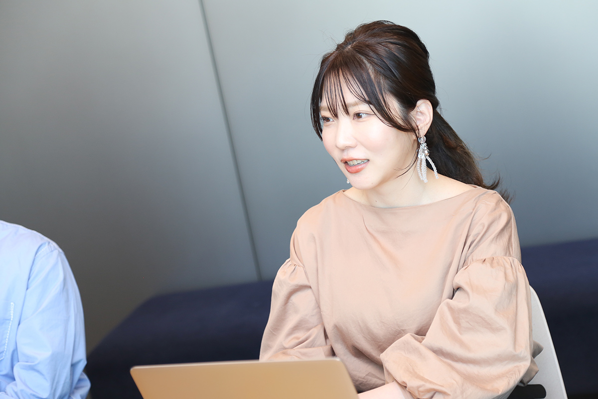 茶色のトップスを着た女性がラップトップを使っている写真です。彼女は真剣な表情で画面を見ています。