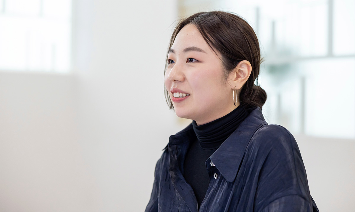 女性が微笑んでいる横顔の写真。明るい室内で撮影されている。
