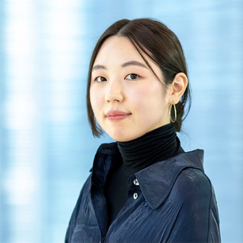 青い背景の前に立つ女性のポートレート写真。
