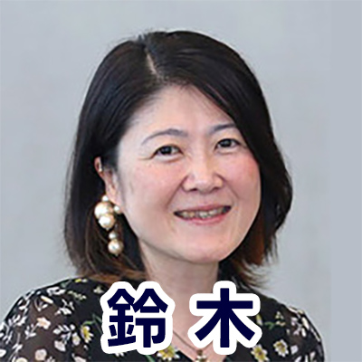 短い髪の女性が微笑んでいる。背景はグレー。「鈴木」と書かれている。