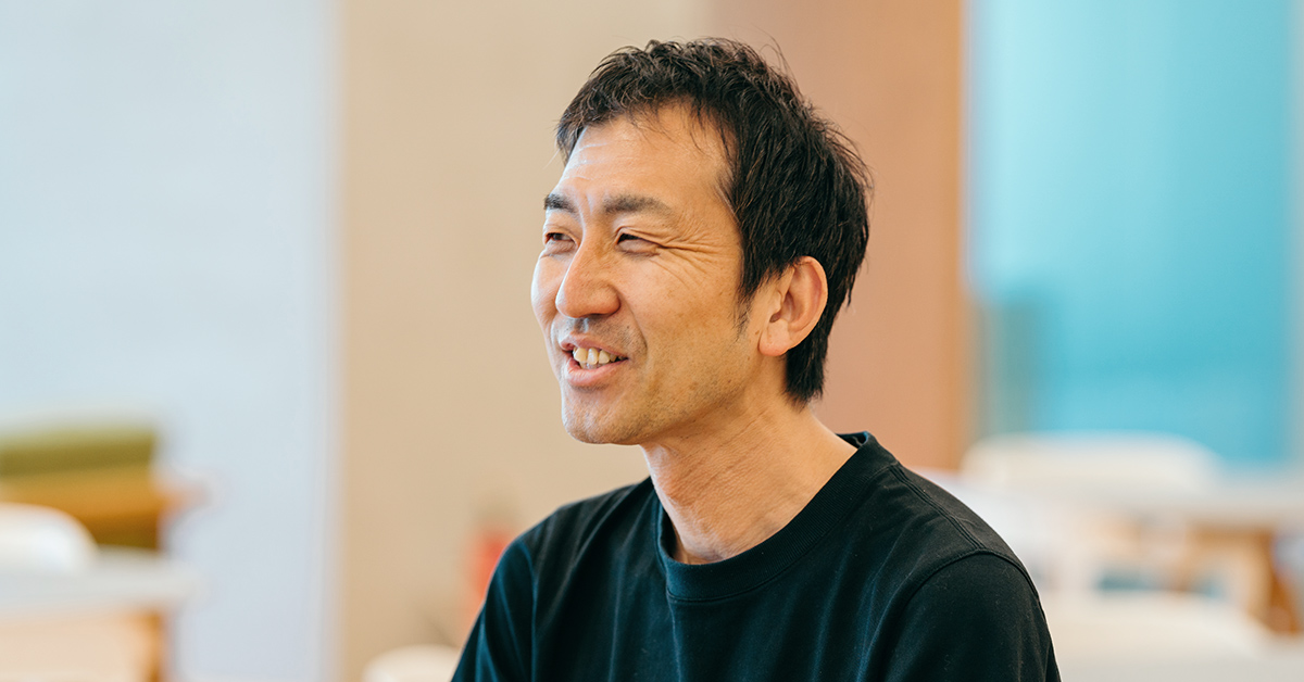 笑顔の男性が室内で横を向いている写真。