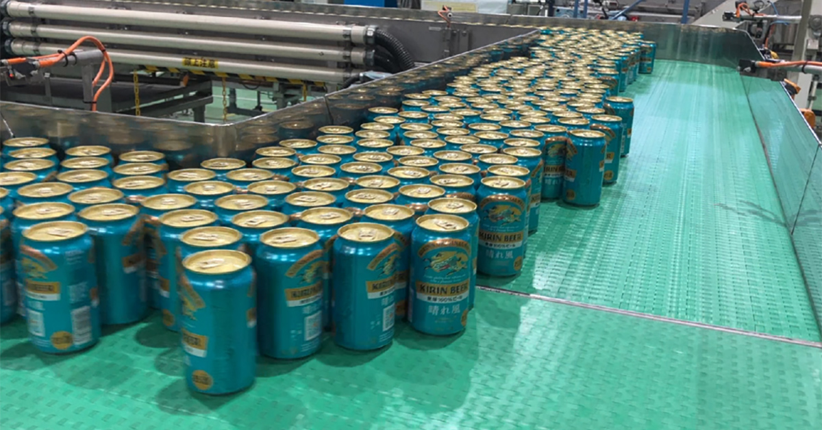 Beer cans are seen lined up on a production line in a factory.