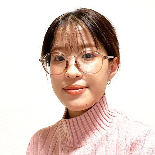 ピンクのセーターを着たメガネの女性のポートレート写真。
