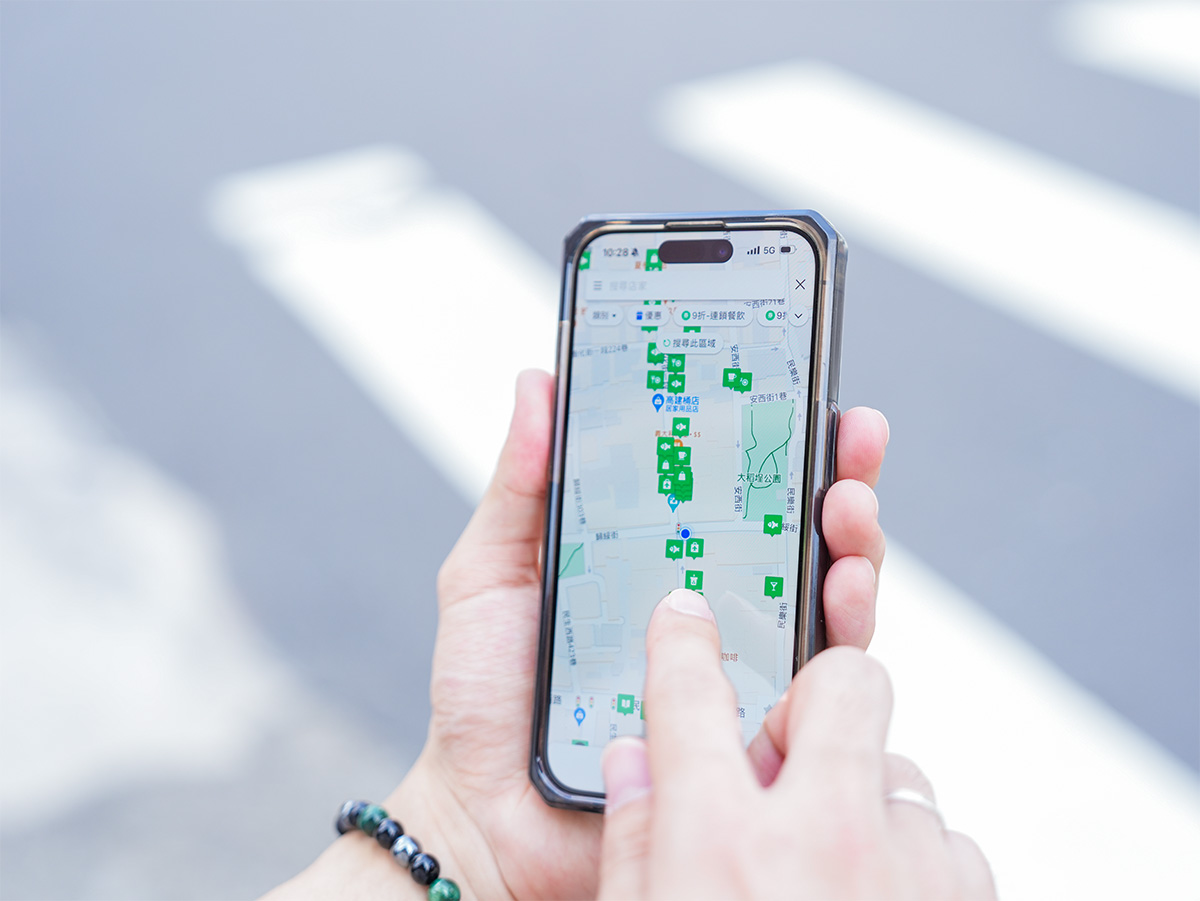 スマートフォンで地図アプリを操作している手元の写真です。画面には多くのランドマークが表示されています。