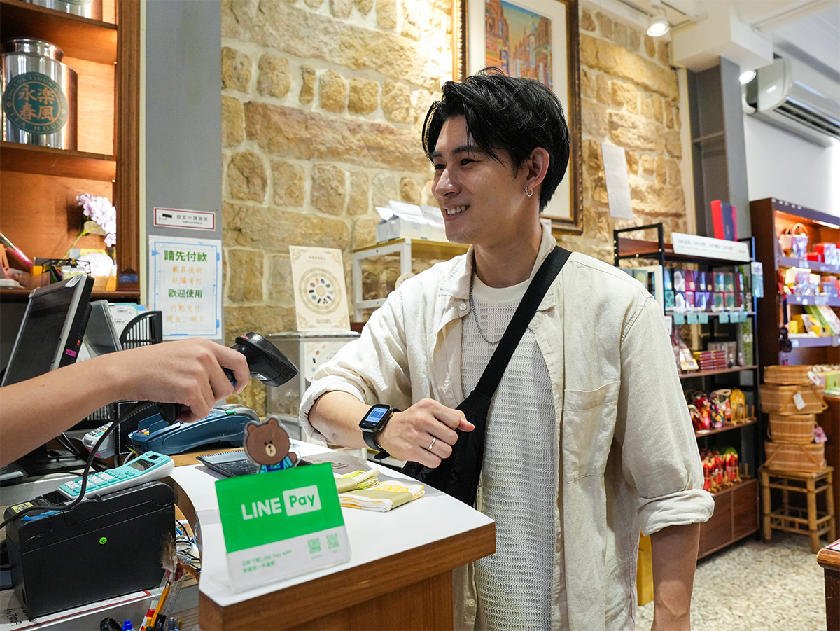 男性がレジで支払いをしている写真です。LINE Payのロゴがカウンターに見えます。