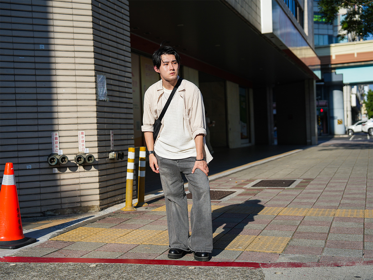 男性が街角で立ち止まり、何かを見ている写真です。周囲には建物と交通が見えます。