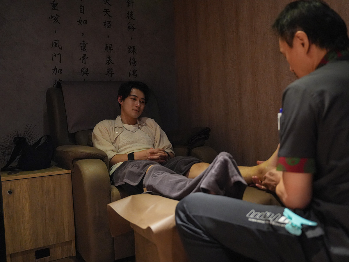 男性がリラックスチェアで足のマッサージを受けている写真です。落ち着いた雰囲気の室内です。