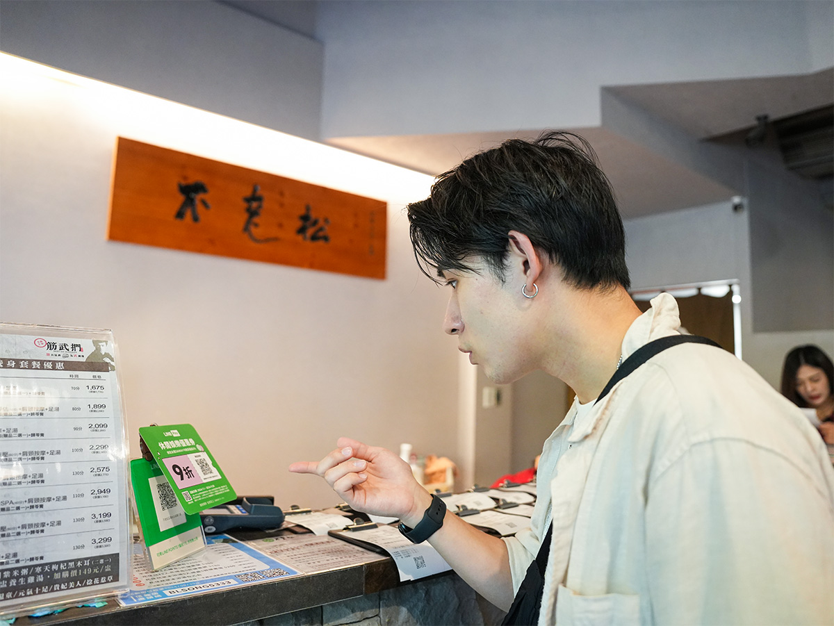 男性がカウンターでメニューを見ている写真です。背景には施設の案内板が見えます。