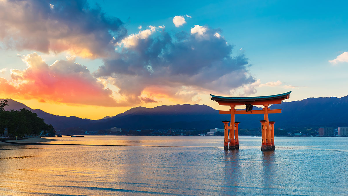 美しい夕焼けの下、海に浮かぶ鳥居が静かに立っている風景が広がっています。