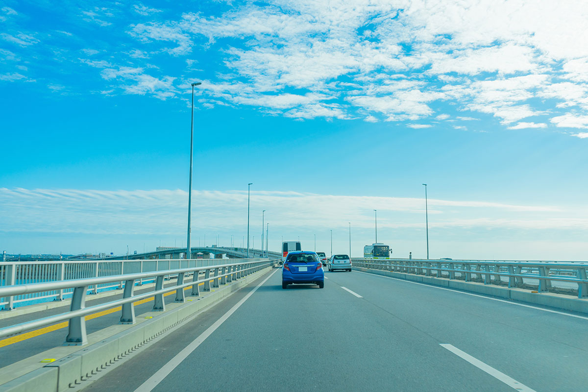 青空の下、車が走る広い橋の風景が広がっています。