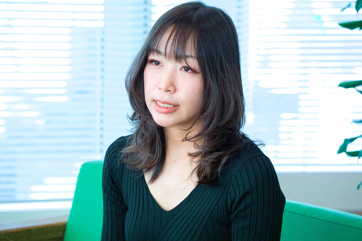 女性が窓際で話している様子です。背景にはブラインドがあり、自然光が差し込んで明るい空間を演出しています。