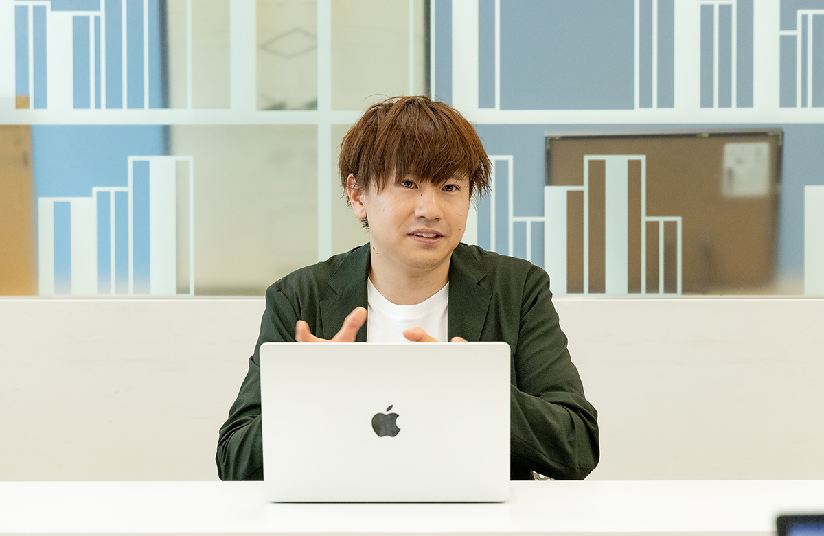 男性がノートパソコンの前で話をしている写真です。彼は真剣な表情で手を動かしています。