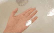水（みず）の中（なか）に手（て）が入（はい）っていて、水面（すいめん）に入浴剤（にゅうよくざい）の泡（あわ）が浮（う）かんでいる写真（しゃしん）