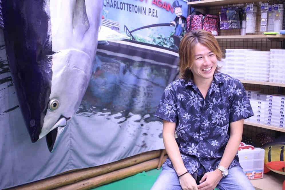 マグロのオブジェの前でインタビューを受ける酒井さん