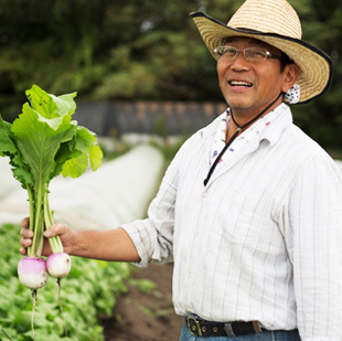 画像:カブを片手に微笑む山口雅行さん