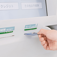  ATMでカードを入れる男性の手の写真