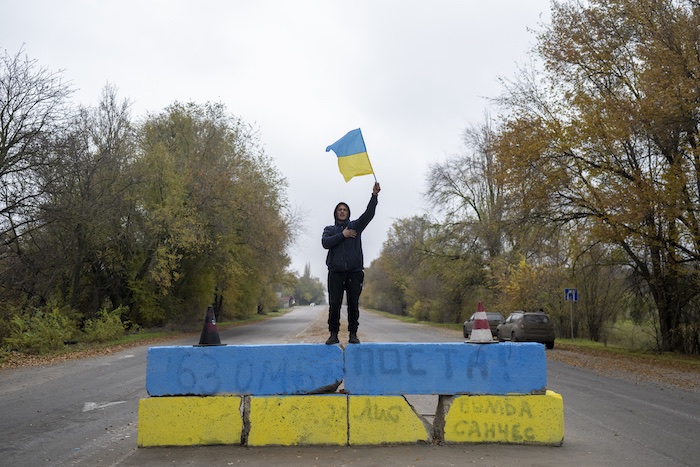 ウクライナ・ヘルソンのロシア軍の検問所だった場所で、ウクライナ国旗を振る人（2022年11月13日撮影）。(c)Bulent KILIC / AFP