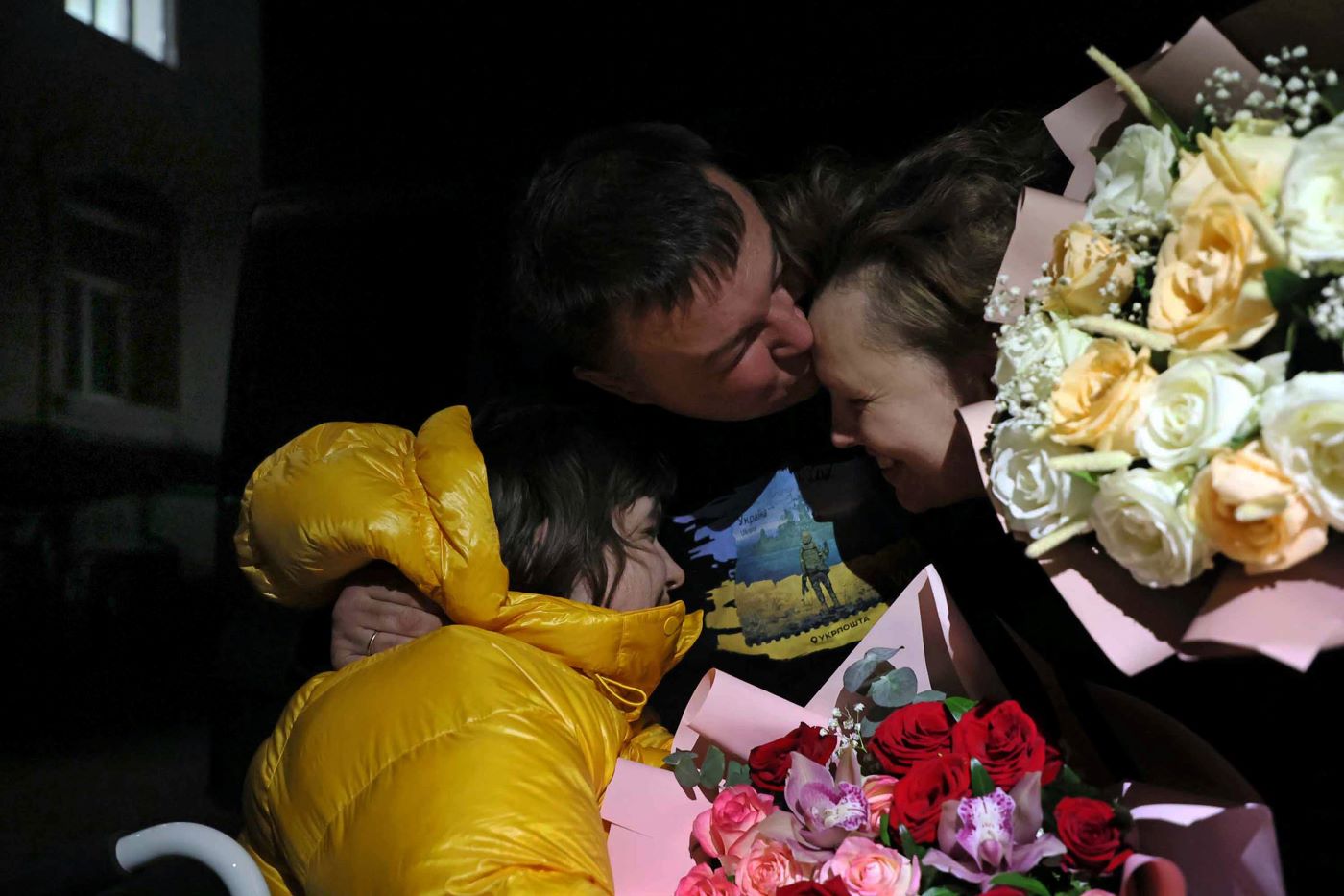 花束を用意して待っていた父ブラディ・イバシェンコさん（中央）とホテルの駐車場で再会したマルタさん（左）と母マリナさん（右）＝ウクライナ･リビウで2023年11月3日